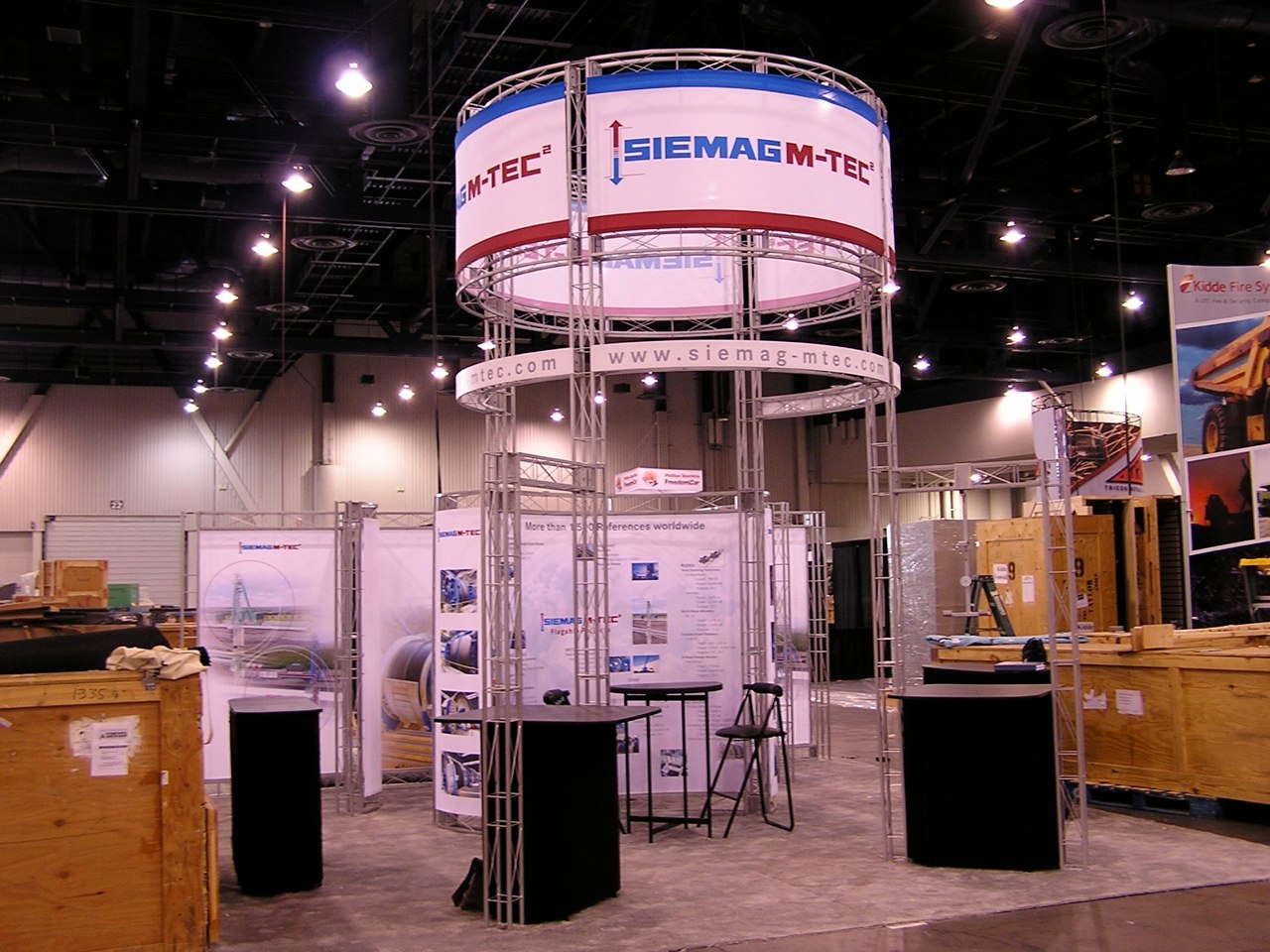 Beautiful trade show island booth space design with workstations and meeting area